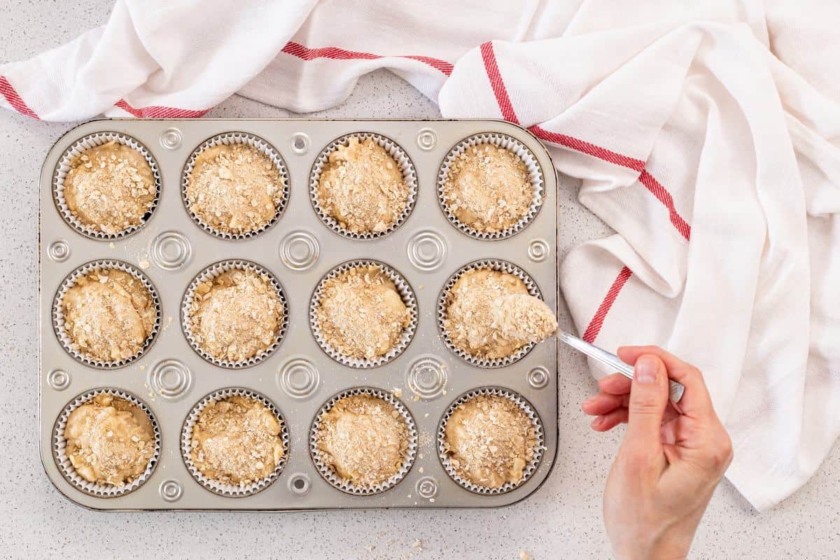 The crumble mixture is sprinkled over the top of the apple pie muffins.