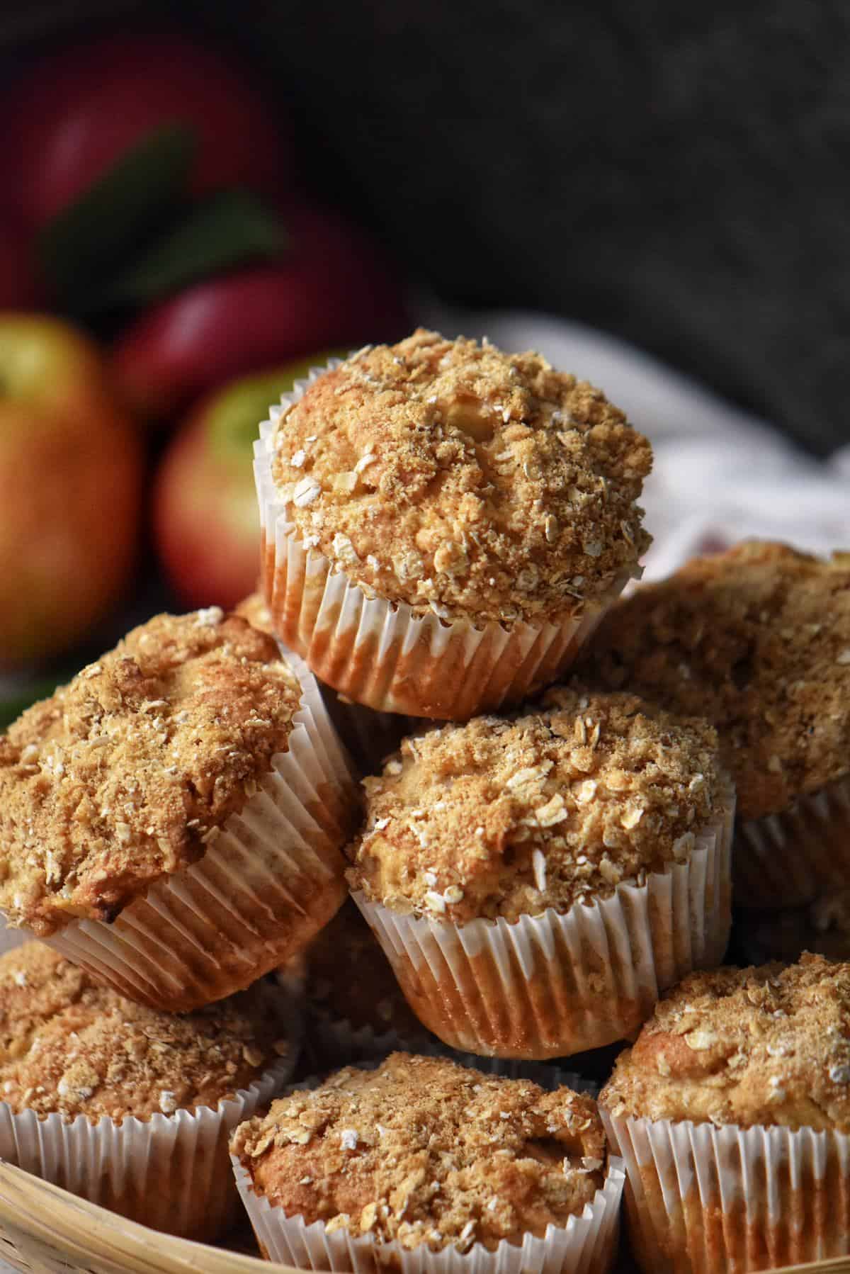 Grated apple muffins with streusal topping piled high on a wicker basket.