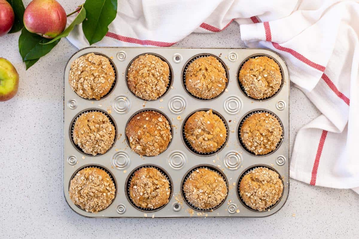 Freshly baked apple muffins in a muffin tray.