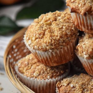 Apple muffins topped with a crumble in a wicker basket.