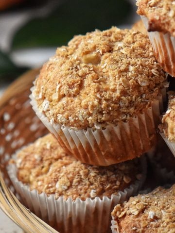 Apple muffins topped with a crumble in a wicker basket.