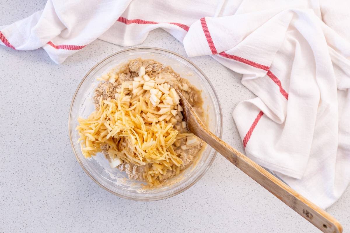 The addition of the chopped and grated apples to the apple muffin batter.