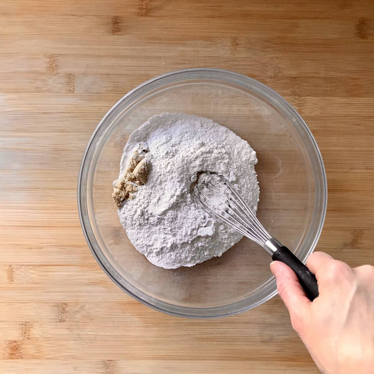 Flour, baking powder, baking soda, salt and brown sugar being whisked together in a bowl.
