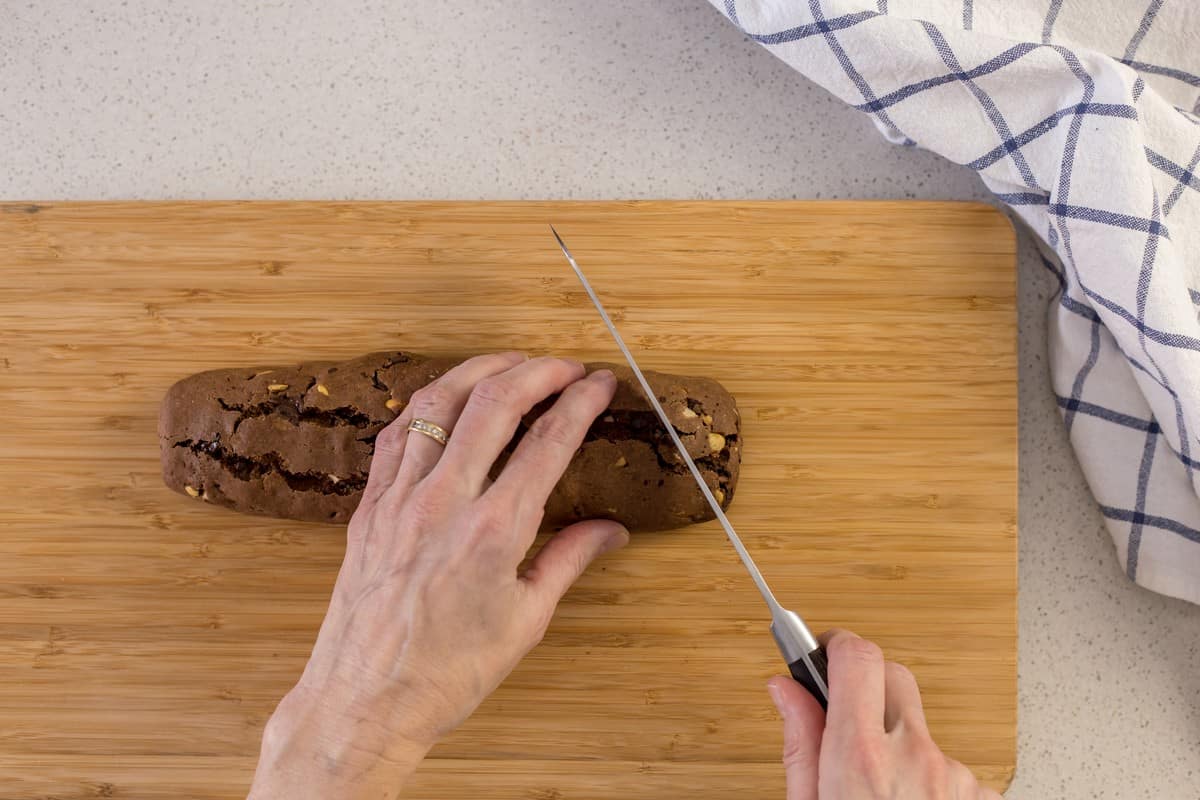 A biscotti log is in the process of being sliced.