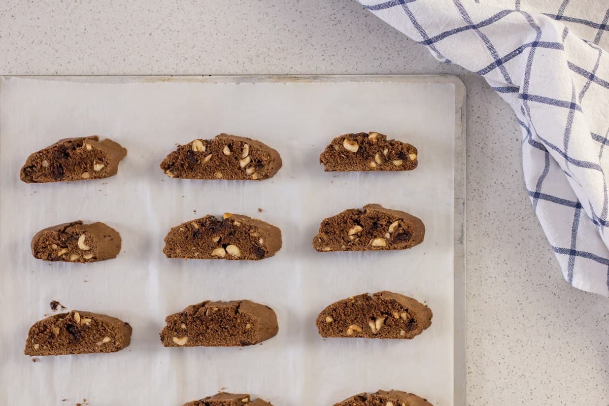 Sliced biscotti placed on a parchment lined baking sheet, ready for the second baking.