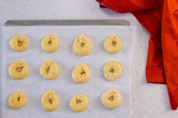 The ring shaped Italian cookies are placed on a parchment lined baking sheet, ready to be baked.