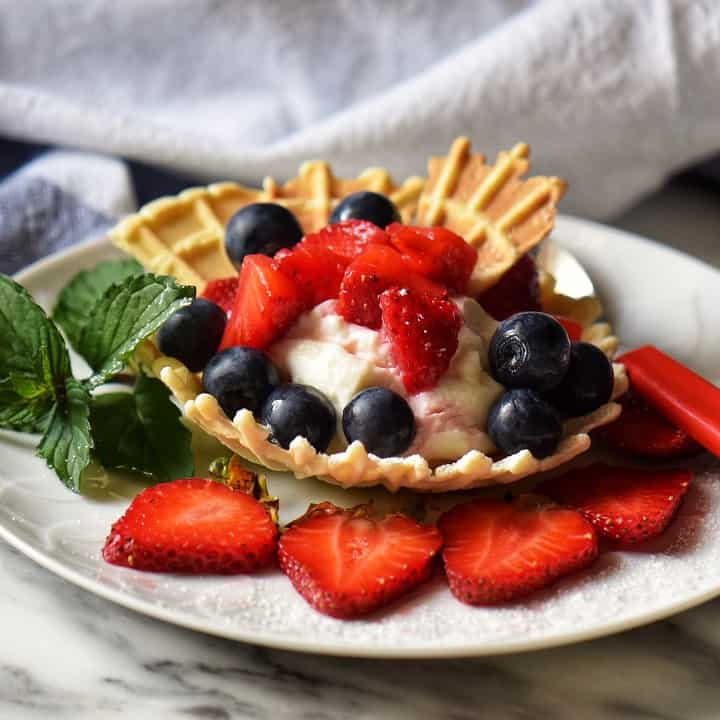 Pizzelle shaped in a bowl and filled with whipped ricotta and macerated strawberries.