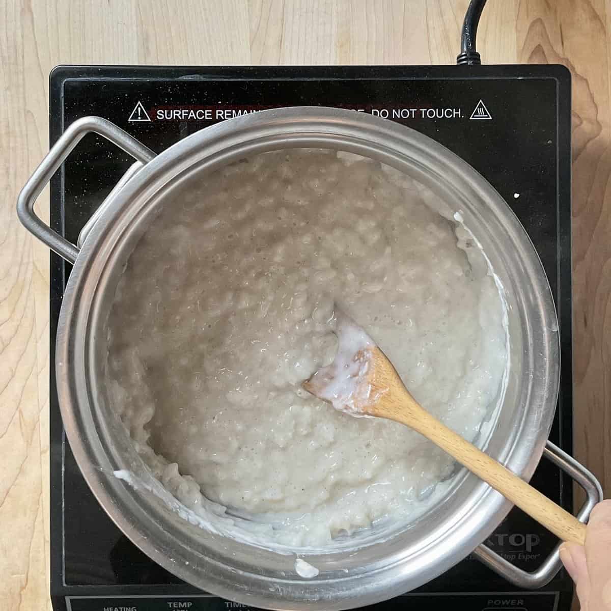 Rice pudding being stirred in a pot.