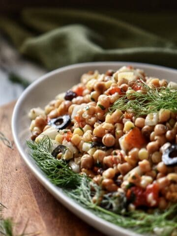 Fregola with roasted red pepper in a white serving dish.