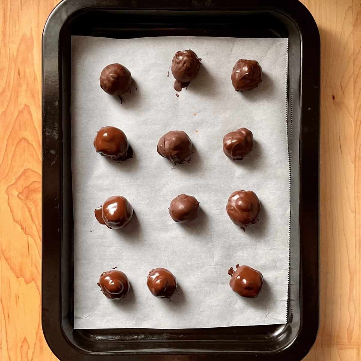 Homemade chocolate hazelnut kisses freshly covered with dark chocolate on a tray.