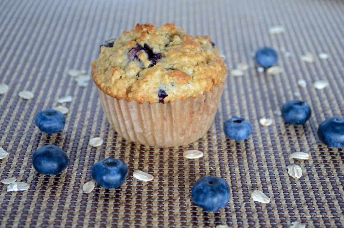 A blueberry muffin surrounded by blueberries and oats.
