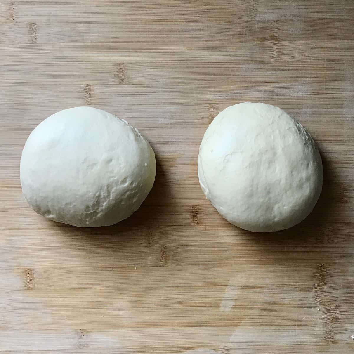 Two balls of dough on a wooden board. 