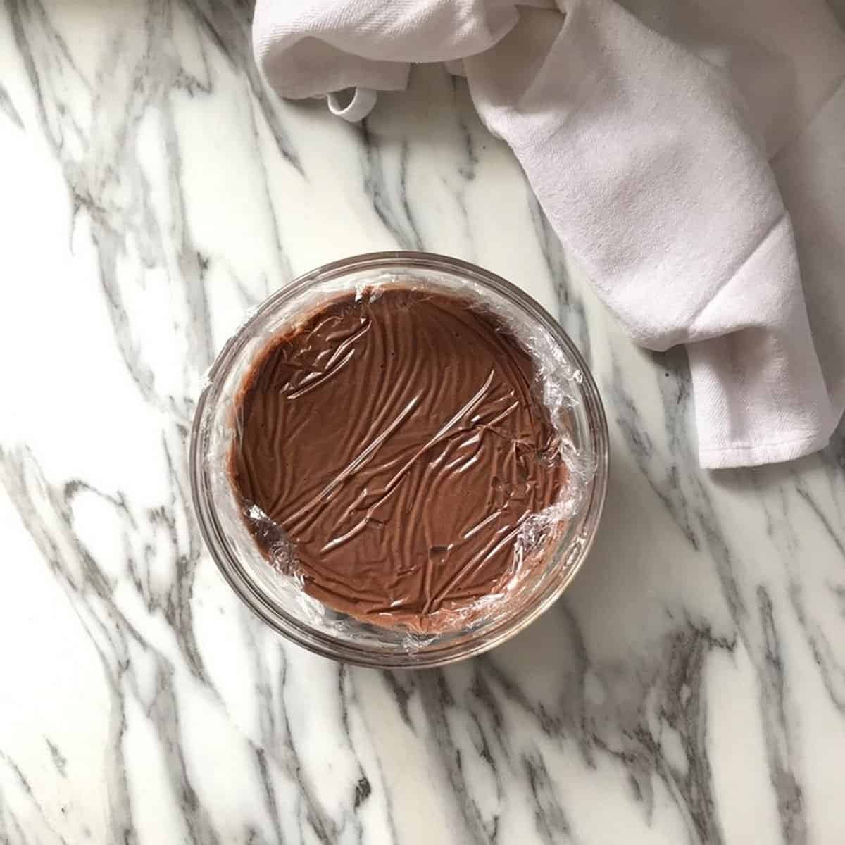 Cellophane is placed directly on the surface of the chocolate pudding.