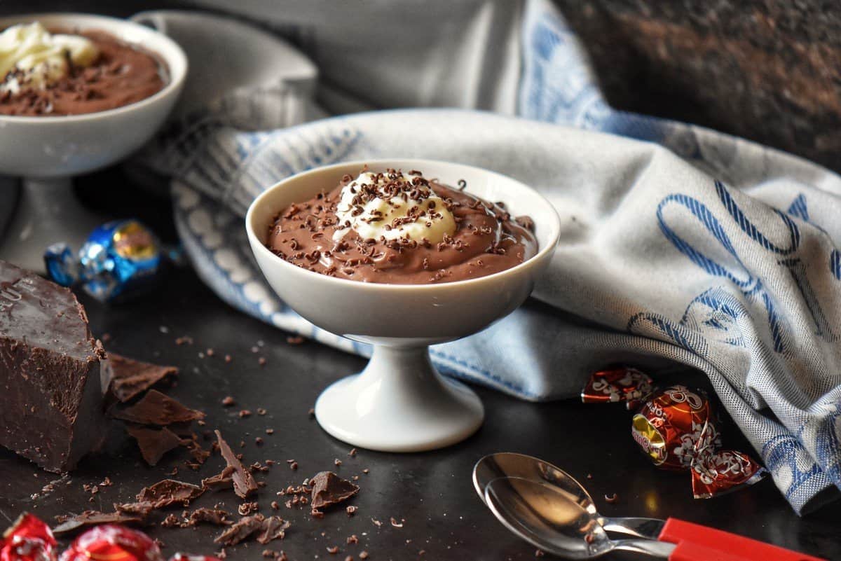 Dark chocolate pudding topped with some whipped ricotta in a white dish.