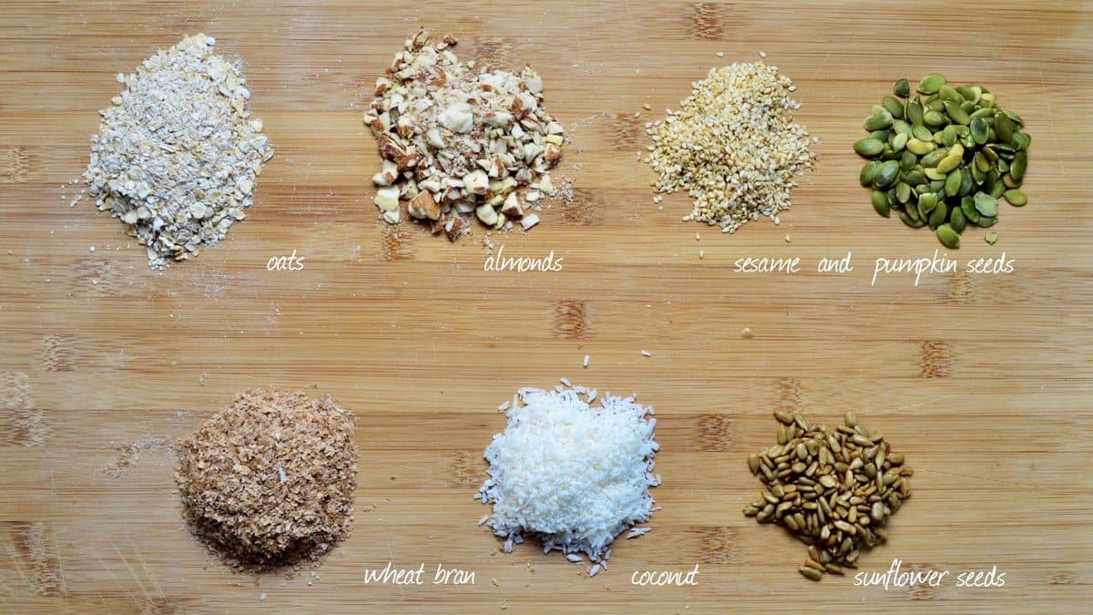 Dry ingredients to make crunchy granola on a wooden board.