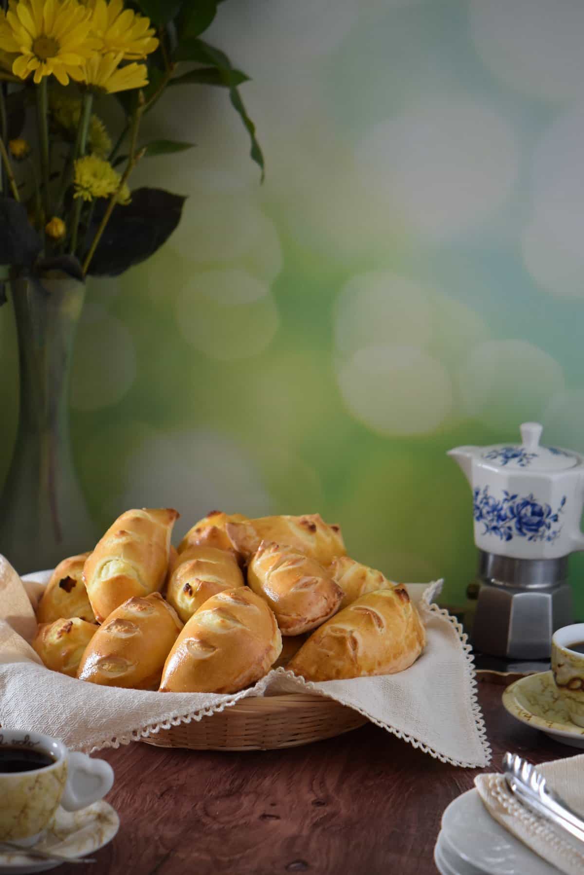 Mini sweet ricotta pies in a wicker basket next to espresso coffee.