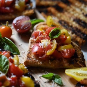Diced tomatoes and basil are used to top grilled bruschetta in order to make a simple Italian appetizer.