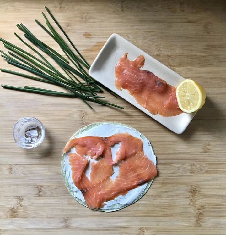 Cream cheese and smoked salmon is spread over a whole wheat tortilla.