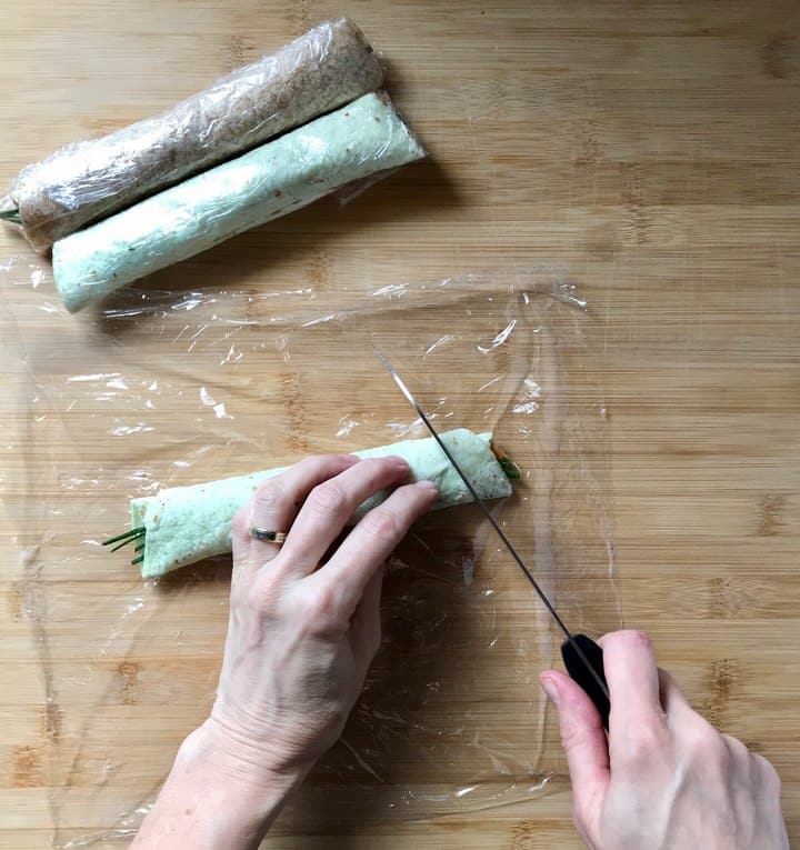 Salmon wraps in the process of being sliced at an angle.