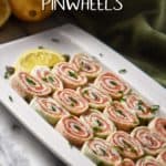 A white serving dish is filled with slices of smoked salmon pinwheels.