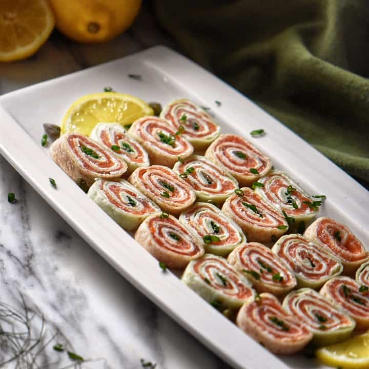 Smoked salmon roll ups garnished with capers and chopped chives.