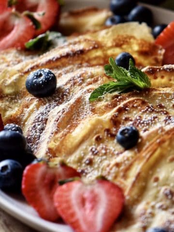 Crepes and berries on a serving platter.