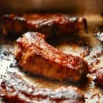 Oven baked ribs generously glazed with Bar-B-Barn sauce, resting on a baking pan.
