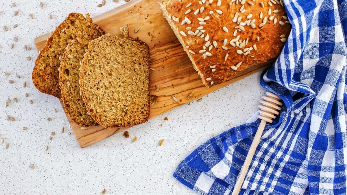 A few slices of a no yeast wheat bread on a wooden board, next to a bread knife.