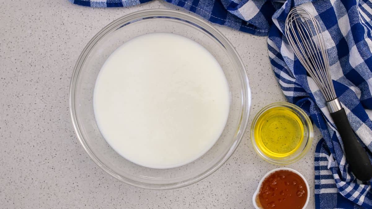 An overhead shot of a bowl of buttermilk, oil and honey.