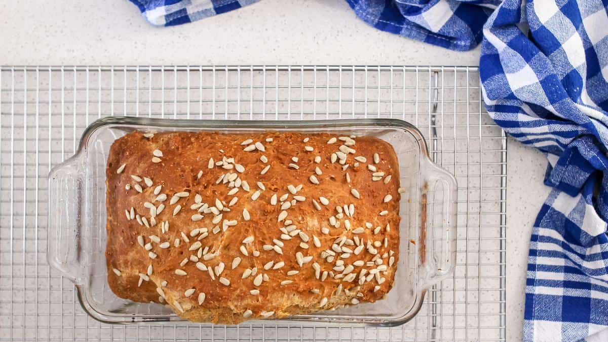 A freshly baked loaf of whole wheat bread on a cooling rack. 