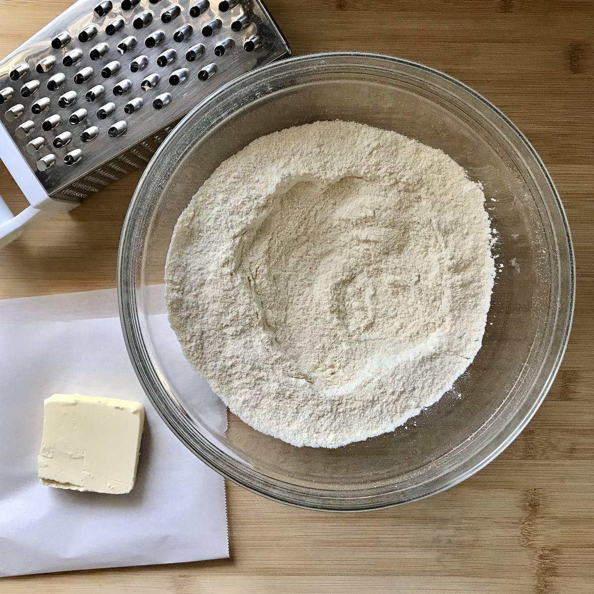 A piece of butter next to the bowl of dry ingredients.