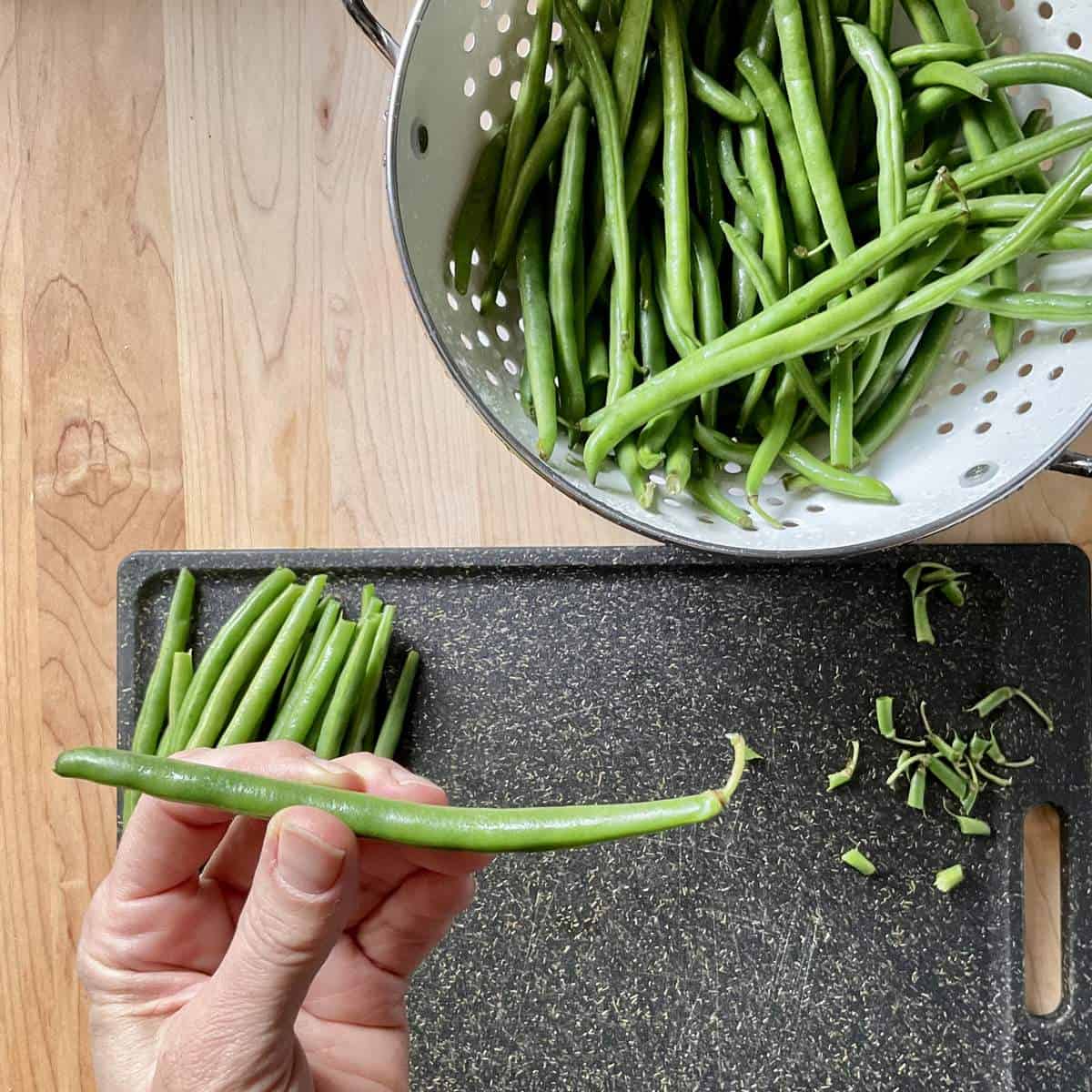 A green bean is held with one hand.