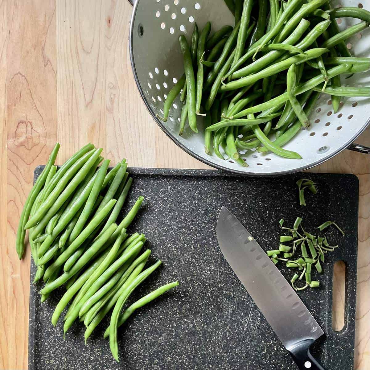 Trimmed grean beans on a cutting board.