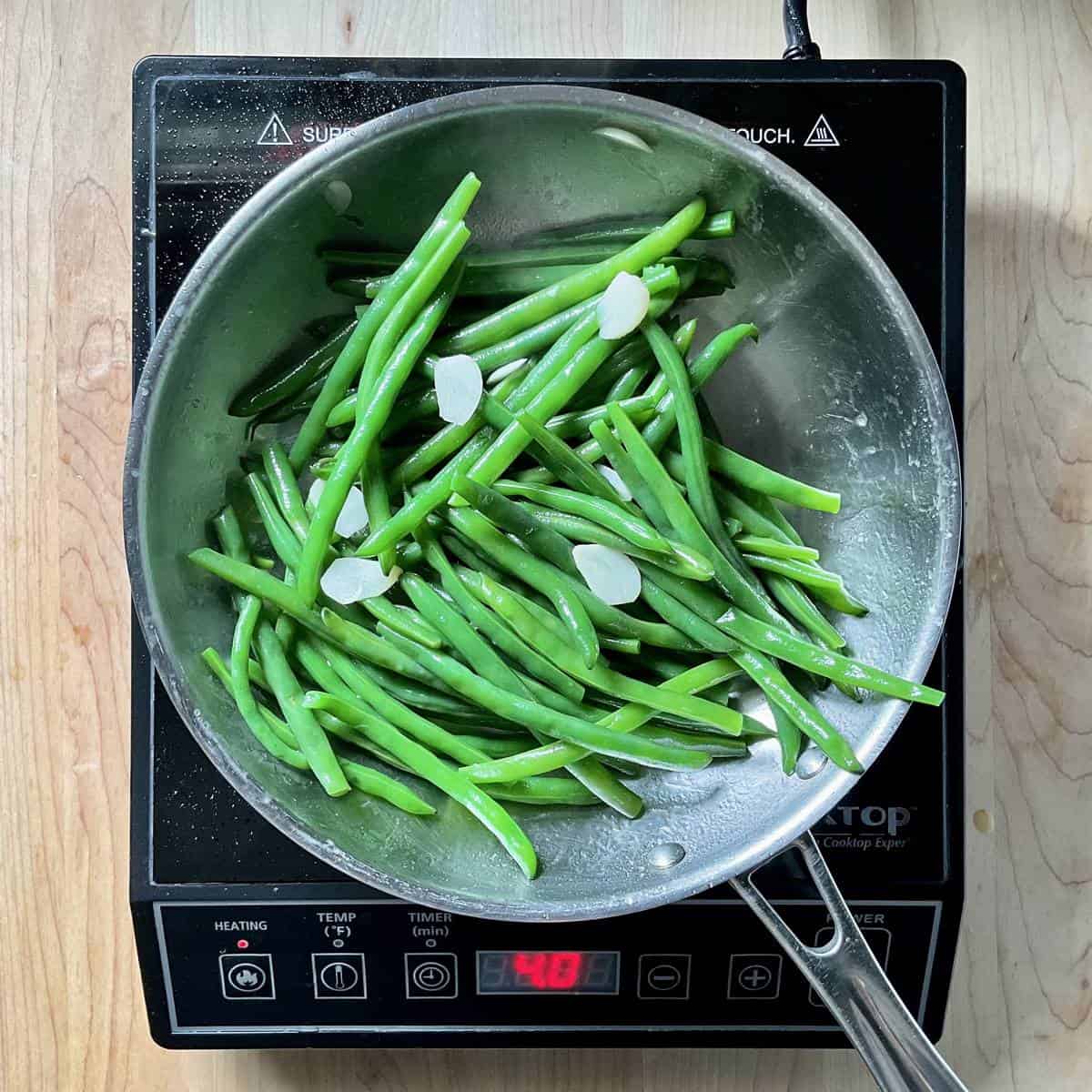 Green beans and sliced garlic in a skillet.