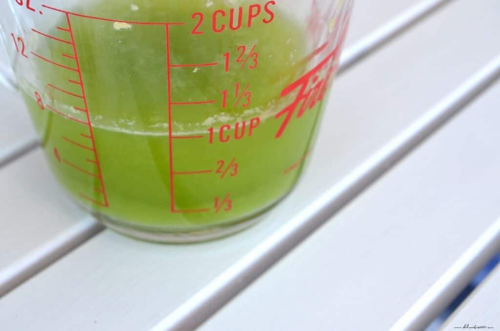 The liquid extracted by squeezing zucchini is collected in a measuring cup.