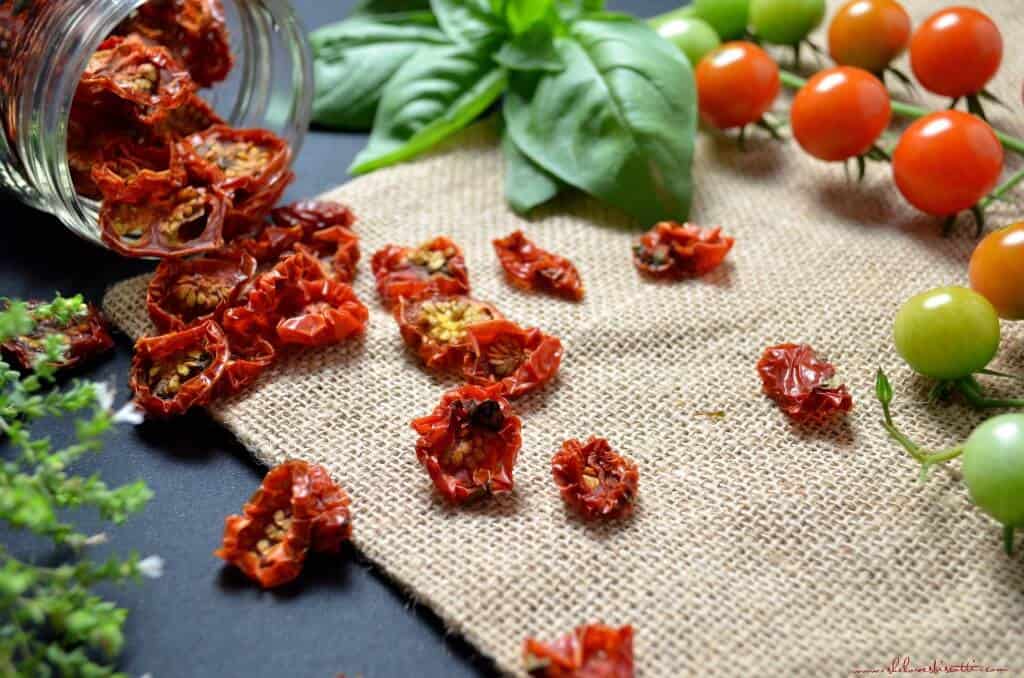 Sun dried cherry tomatoes spilling out of an open jar. 