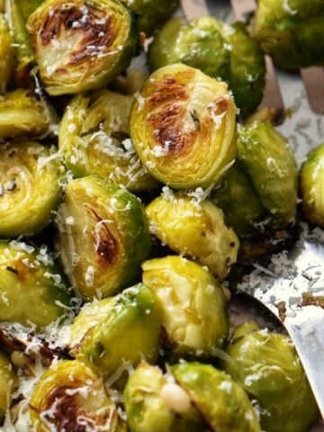 Brussel sprouts garnished with fresh rosemary and roasted pine nuts.