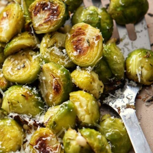 Brussel sprouts garnished with fresh rosemary and roasted pine nuts.