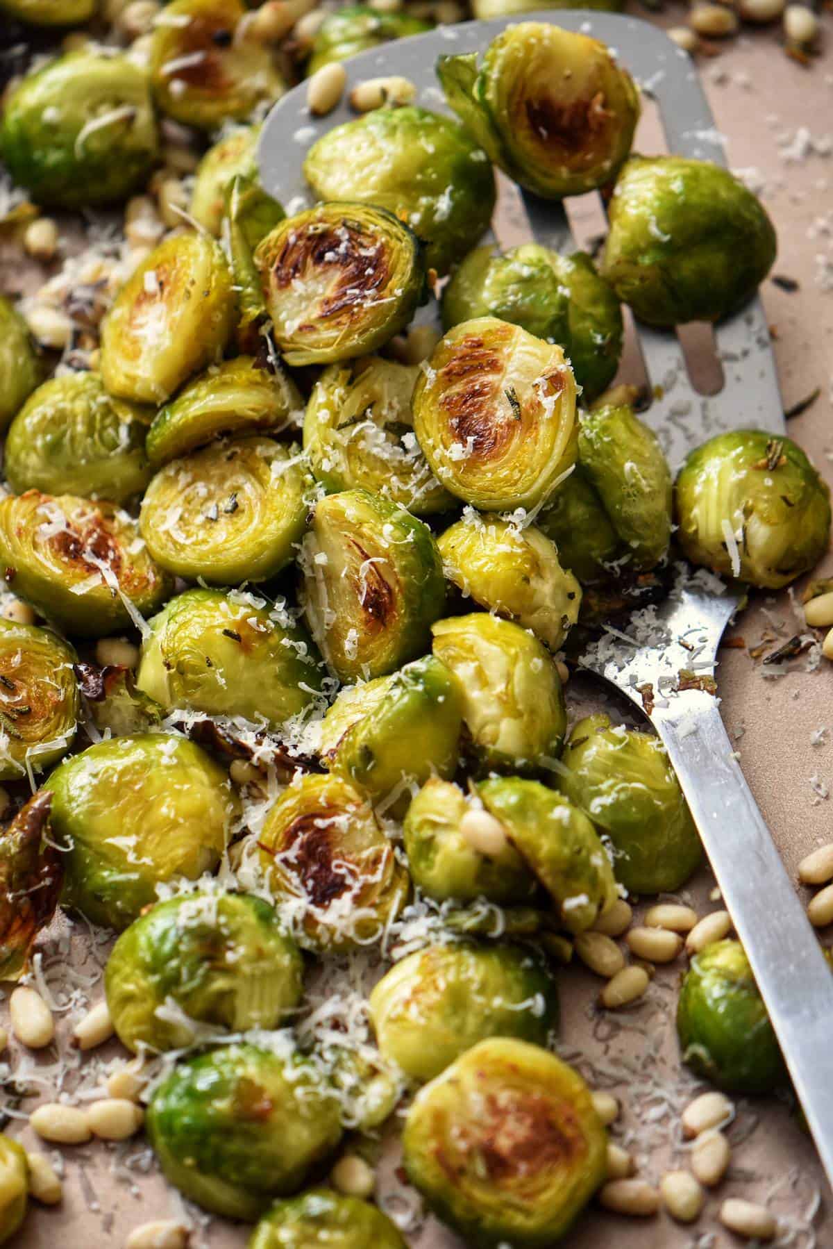 Roasted brussels sprouts with garlic and pine nuts on a sheet pan.
