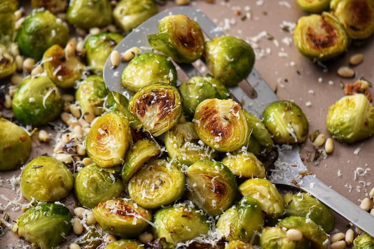 Roasted Brussels sprouts on a sheet pan with grated Parmesan cheese grated over the top.