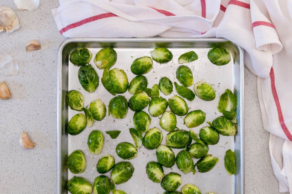 Brussels sprouts placed flat side down on a pan sheet, ready to get roasted.