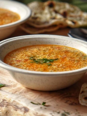 A bowl of Italian Egg Drop Soup on a wooden board.