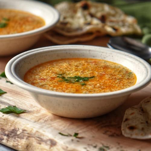 A bowl of Italian Egg Drop Soup on a wooden board.