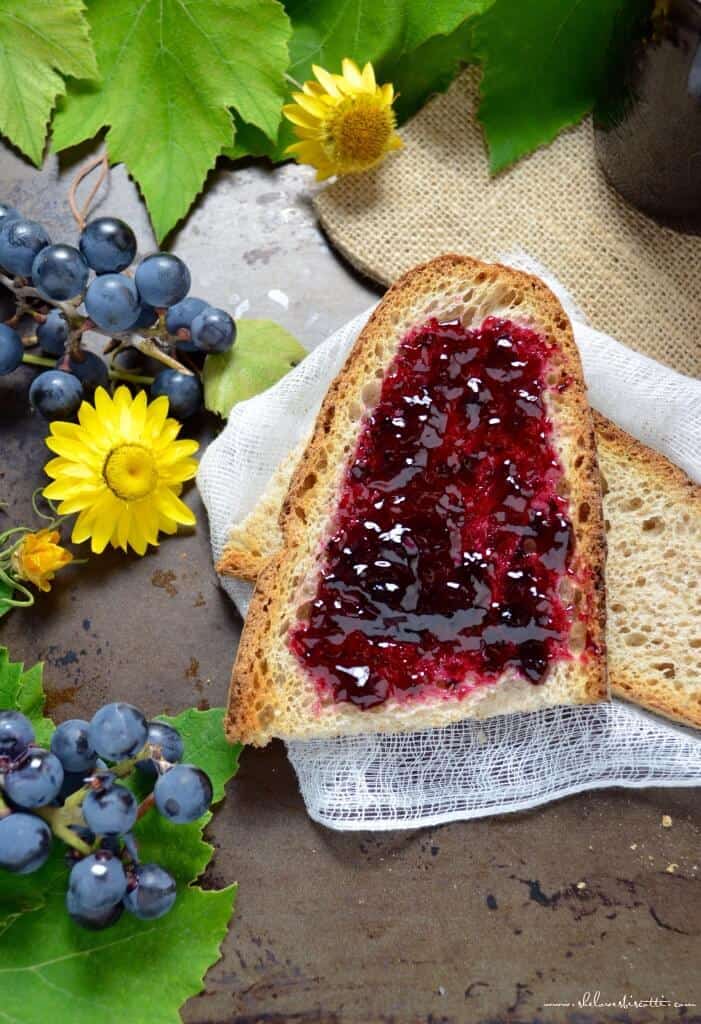 An overhead shot of concord grape jelly spread on a piece of whole wheat bread.