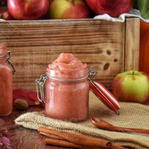 A jar of apple butter next to a wooden spoon.