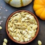 Slow roasted pumpkin seeds in a brown dish.