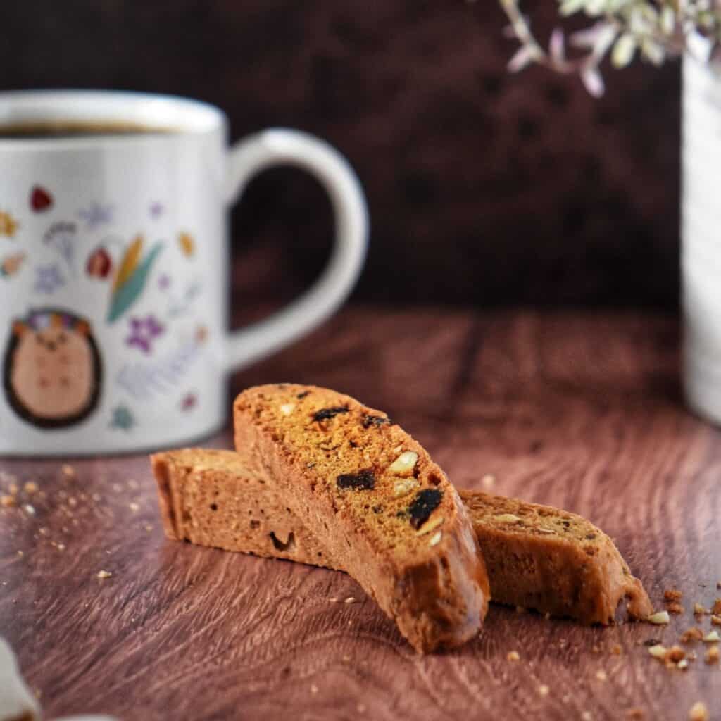 Two date and almond biscotti next to a mug of coffee.