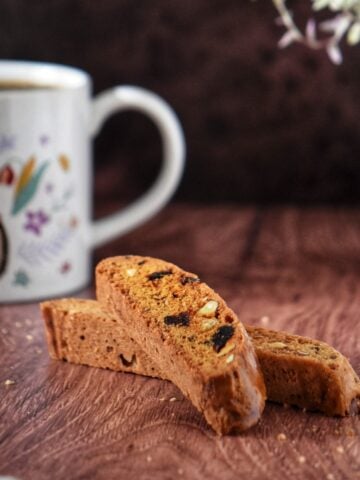 Two date and almond biscotti next to a mug of coffee.