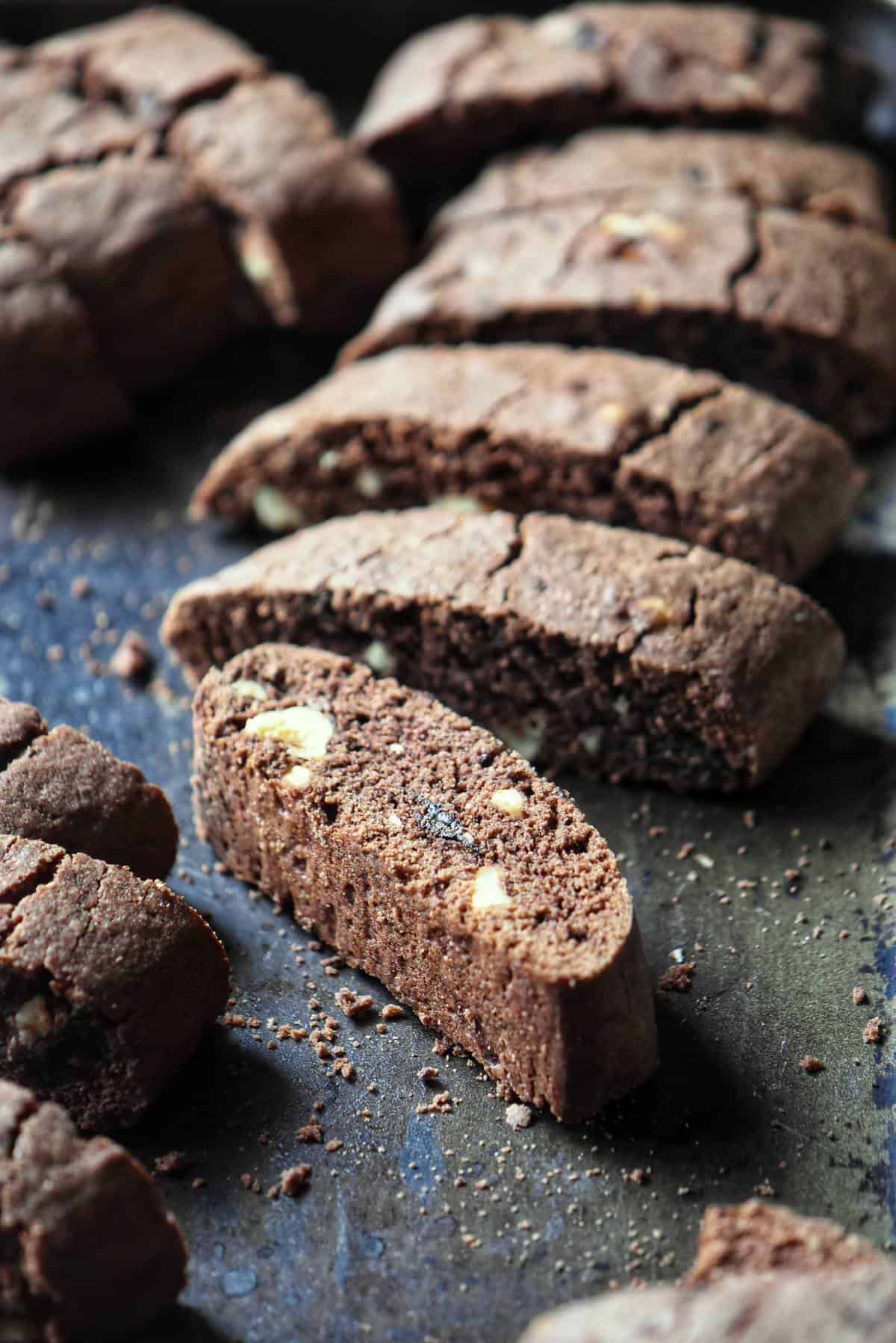 Sliced chocolate biscotti on a dark surface. 