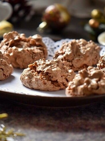 A tray of brutti ma buoni cookies on a table surrounded by Christmas decor.